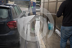 Man Using Water Pressure Machine to Wash a Car