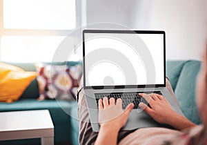 Man using, working on laptop with blank screen while lying on sofa in living room