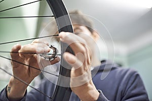Man using a wrench to tighten the spokes of a bicycle wheel in his bike workshop