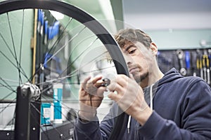 Man using a wrench to tighten the spokes of a bicycle wheel in his bike workshop