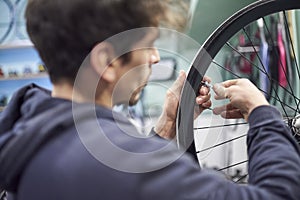 Man using a wrench to tighten the spokes of a bicycle wheel in his bike workshop