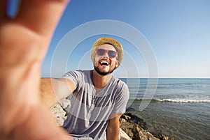 Man on vacation laughing at the beach taking selfie