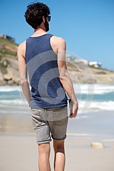 Man on vacation walking alone on beach with book