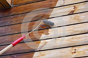 Man varnishing wooden boards with a bow roller and foam roller