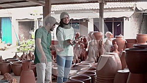 Man and veiled woman discussing at their pottery workshop