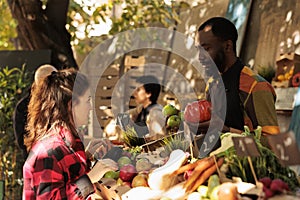 Man vendor standing behind stall selling fresh organic vegetables