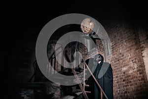 A man in a Venetian plague doctor mask against the backdrop of an ancient house.