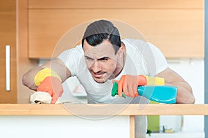 Man is very diligent dusting and cleaning the kitchen