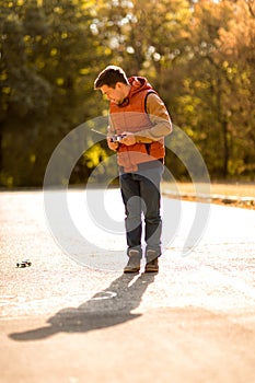 Man in vest playing with toy car on remote control in autumn Park