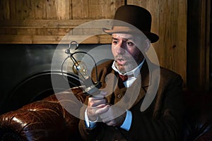 A man in a Victorian hat and suit is looking at a light bulb in his hand in a retro-style salon.