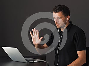 Man in Video conferencing call via laptop and greeting colleagues.