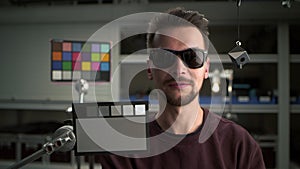 Man in video studio testing professional film camera by Color Checker Card