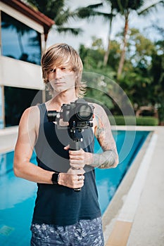 Man videographer is standing outdoors with his camera and gimbal