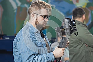 Man videomaker works on news conference modern video camera with a digital display recording an interview on event. Mass