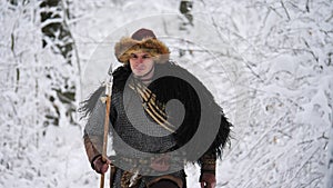 Man viking going in the winter forest.