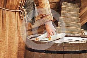 A man in vintage medieval clothes with a paper letter in his hand. Reco