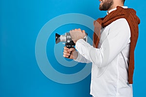 Man with vintage video camera on blue background, closeup. Space for text