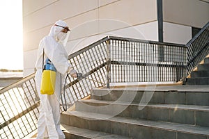 Man in virus protective suit and mask disinfecting buildings with the sprayer.