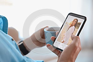 Man visiting dating site via smartphone indoors, closeup