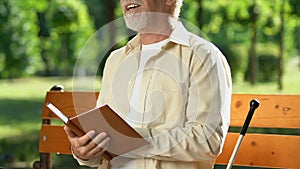 Man with visual impairment smiling reading book in Braille, pleasure moments