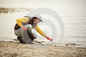 Man volunteer lift off garbage in beach. Coastline environment pollution, outdoor trash and rubbish