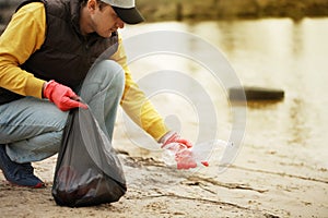 Man volunteer lift off garbage in beach. Coastline environment pollution, outdoor trash and rubbish