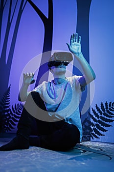 Man with VR glasses sitting on the virtual reality escape room floor