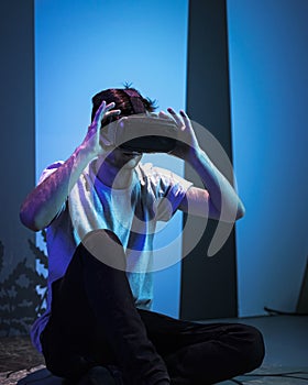 Man with VR glasses sitting on the virtual reality escape room floor