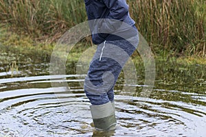 Man wadding through water wearing wellington boots