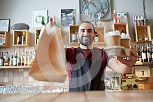 Man or waiter with coffee and paper bag at bar