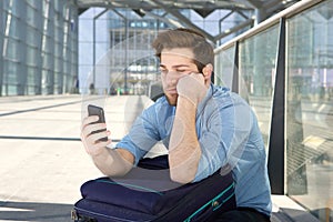 Man waiting at airport with bored expression on face