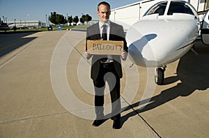 Man waiting for a bailout in front of a corporate photo
