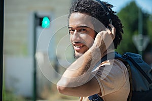 man waiting to cross road wearing headphones