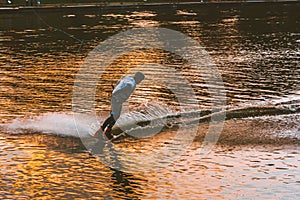 Man wakeboarding on river lake at sunset. Wakeboarder making tricks