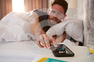 Man Waking Up In Bed Reaches Out To Turn Off Alarm On Mobile Phone