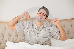 Man waking up in bed and stretching his arms