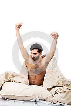 Man waking up in bed and stretching his arms.
