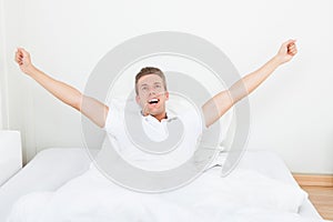 Man waking up in morning and stretching on bed