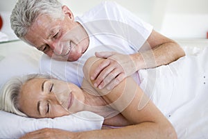 Man waking woman lying in bed sleeping