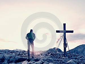 Man walk along the wooden cross at a mountain peak built to Alps victiims. Cross on top