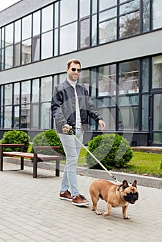 Man walk with french bulldog on leash on urban street