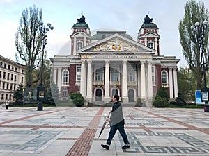 A man walk in front of Ivan Vazov National Theatre, Sofia, Bulgaria