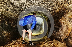 Man walk in low mystical ancient tunnel from orange sandstone.