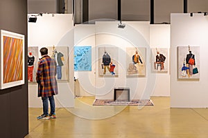 Man Walking and Admiring Paintings in a Modern Art Gallery