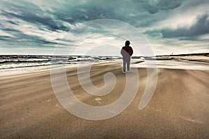 Man walking alone on the beach on windy stormy day