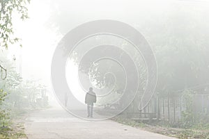 Man walking alone  in the fog in winter in a street in rural Asia