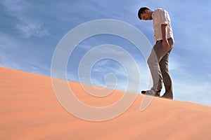 Man walking alone in the sunny desert. He is lost and out of breath. No water and energy.