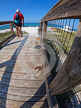 A man walking along a wooden path to the beach at Rosemary Beach, Florida