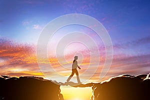 Man walking on another man over precipice between mountains