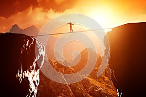 Man walking and balancing on rope over precipice